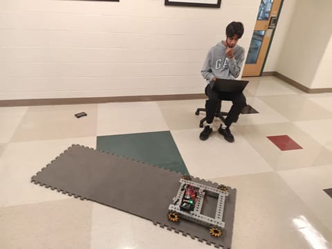 A student with a laptop watching the robot in the hallway