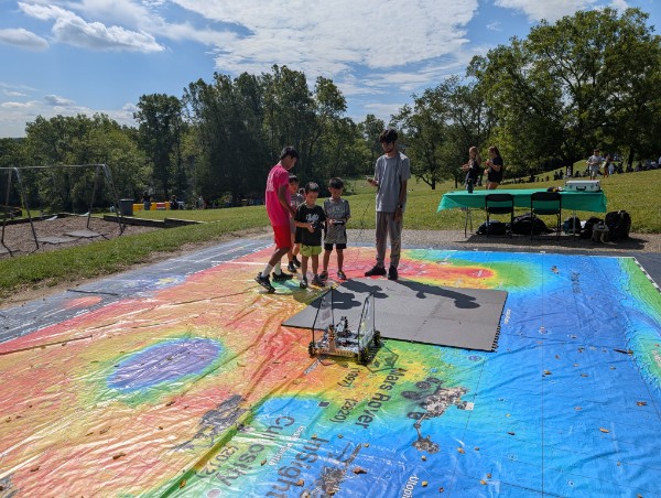 Families gathered around the map watching the robot