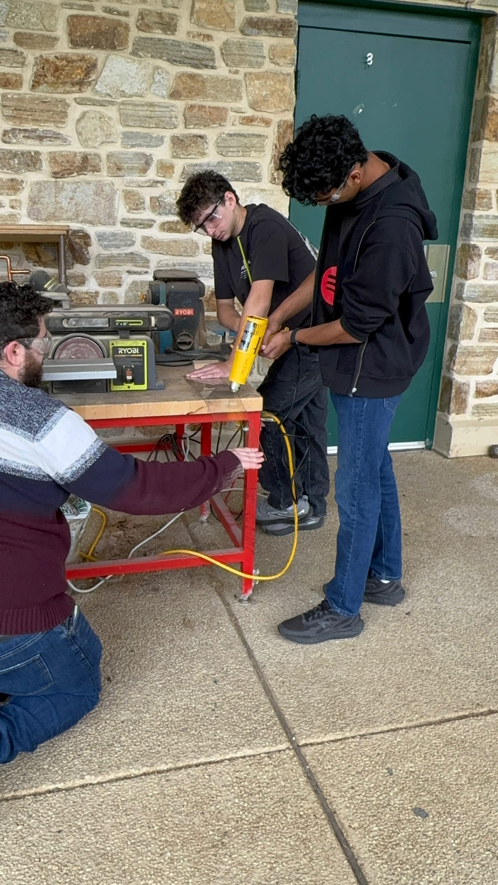 Students heating a sheet of plexi with a heat gun