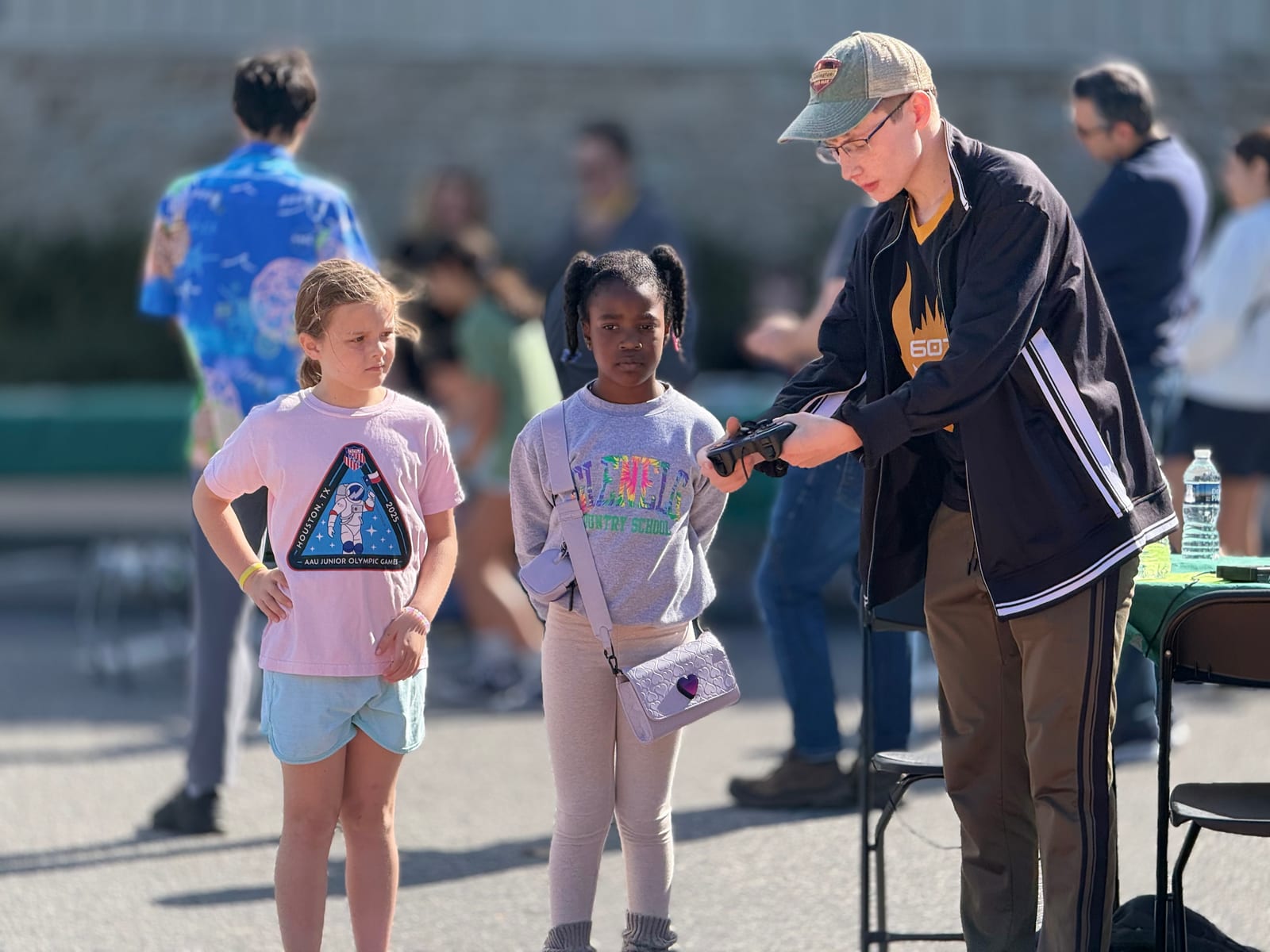 An adult handing a controller to two young visitors